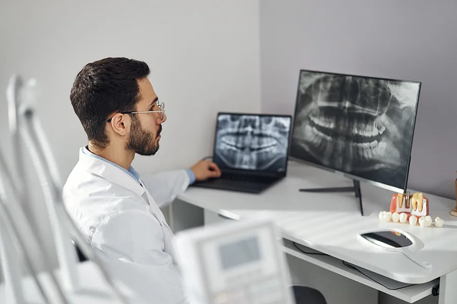 Dental specialist reviewing panoramic X-rays and treatment information — representing patients who may search by symptoms or concerns before knowing which dental treatment or specialist they need.