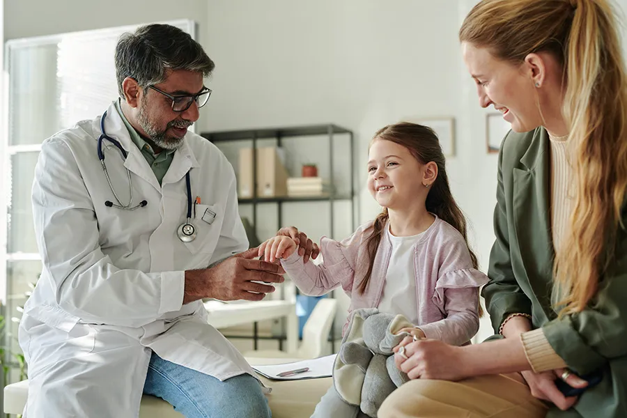 Doctor examining a child with a parent present — representing pediatric and family healthcare practices that need SEO strategies built around their own patients, services, and growth goals.